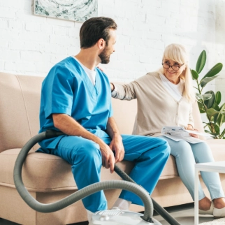 A male caregiver and a senior woman sitting on a couch