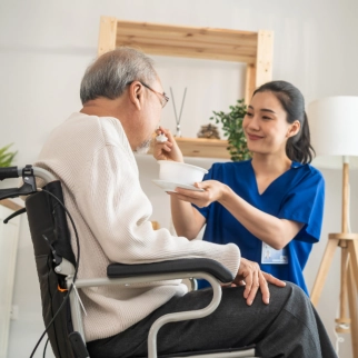 A female caregiver feeding a senior man