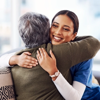 A senior woman hugging the female caregiver