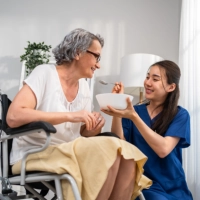 A female caregiver feeding the senior woman