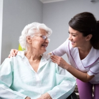 A senior woman and a female caregiver looking at each other