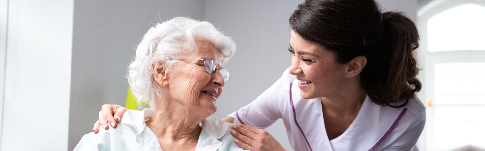 A senior woman and a female caregiver looking at each other