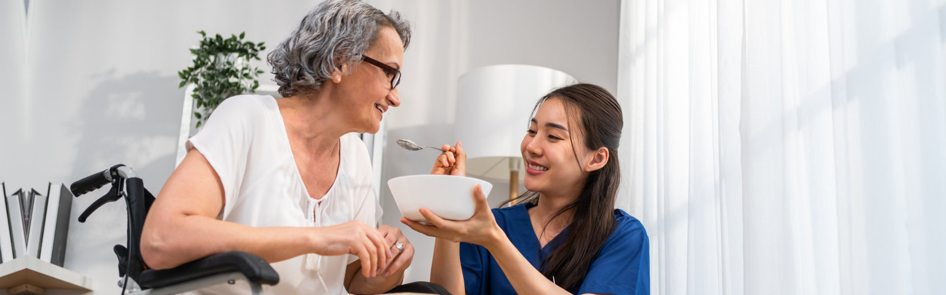 A female caregiver feeding the senior woman