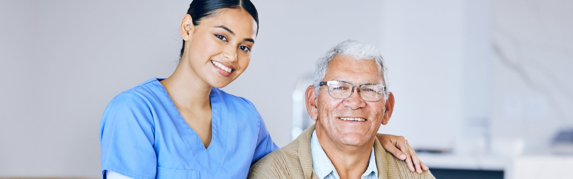 A female caregiver and a senior man sitting on a wheelchair