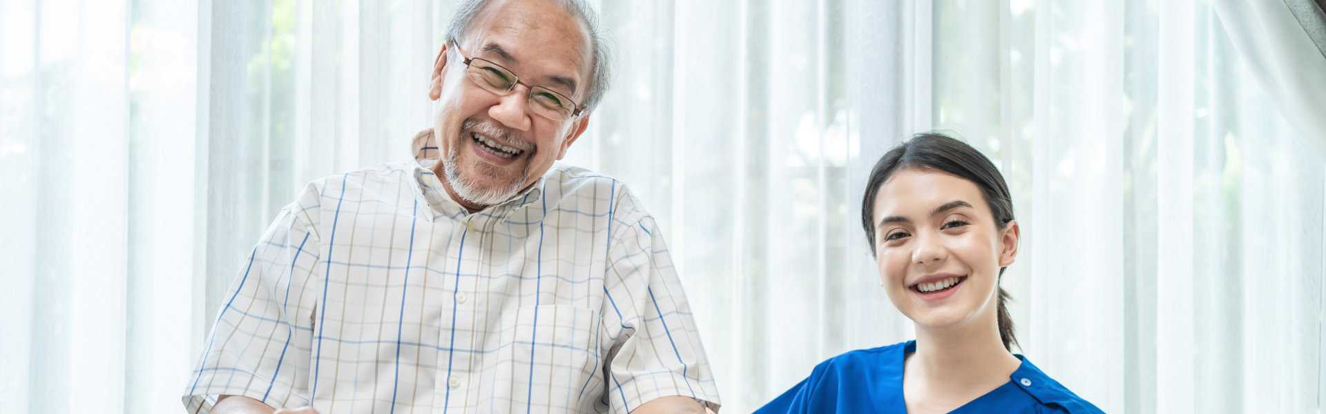 A senior man sitting on a wheelchair and a female caregiver beside him