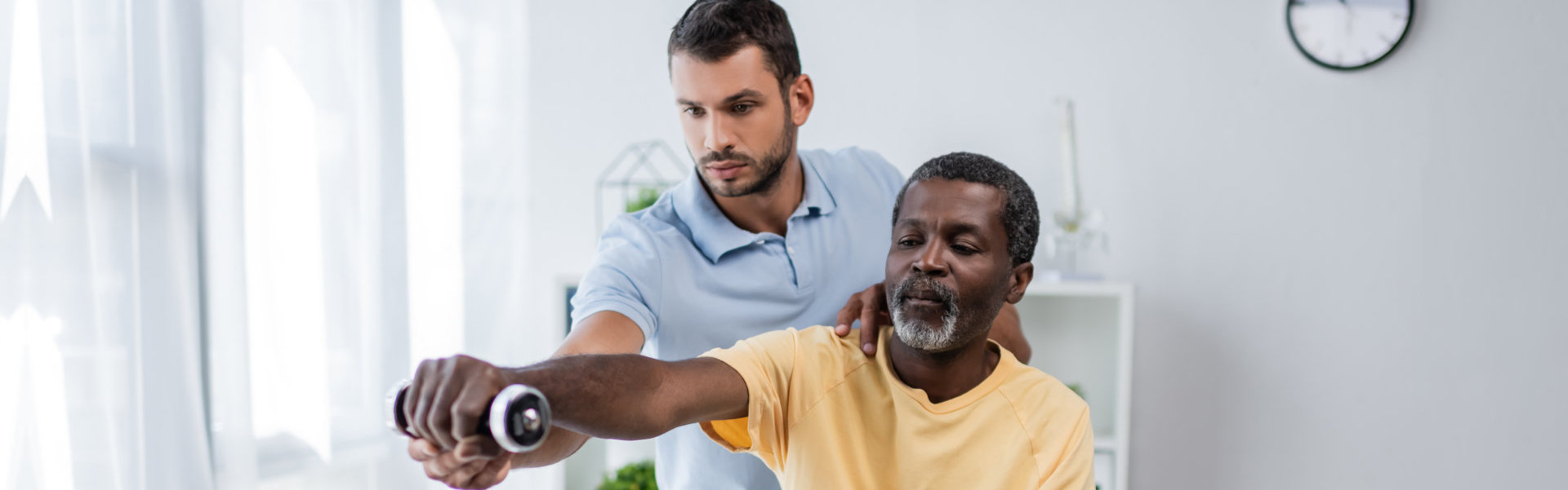 A male assisting a senior man in doing some exercises